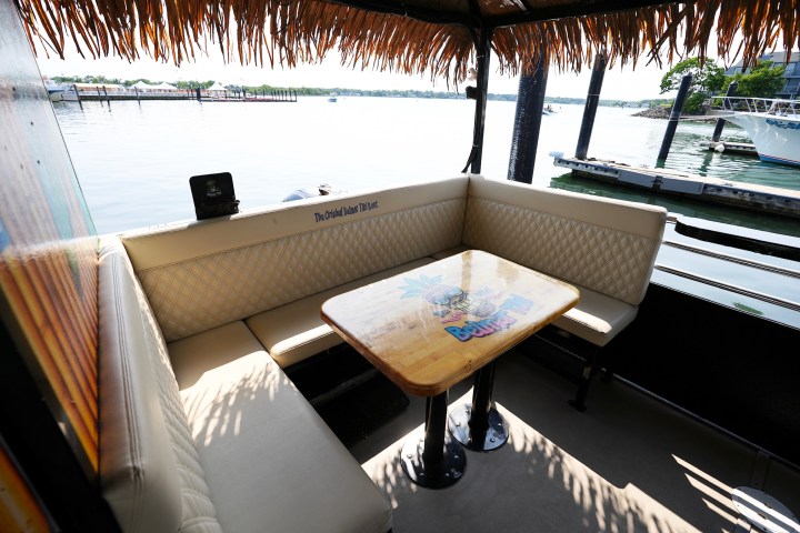 Tiki-style boat seating area with water and dock in the background.