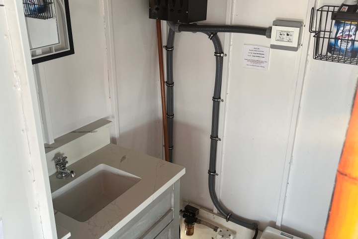 Compact bathroom with sink, mirror, and toilet in white-walled room.