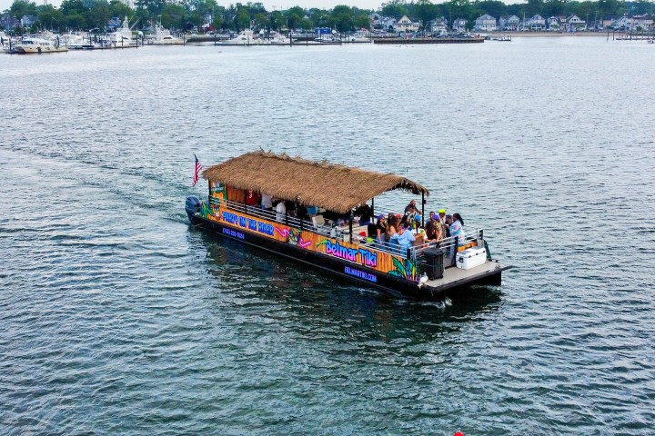 Boat with tropical-themed decor and passengers cruising on a calm lake.