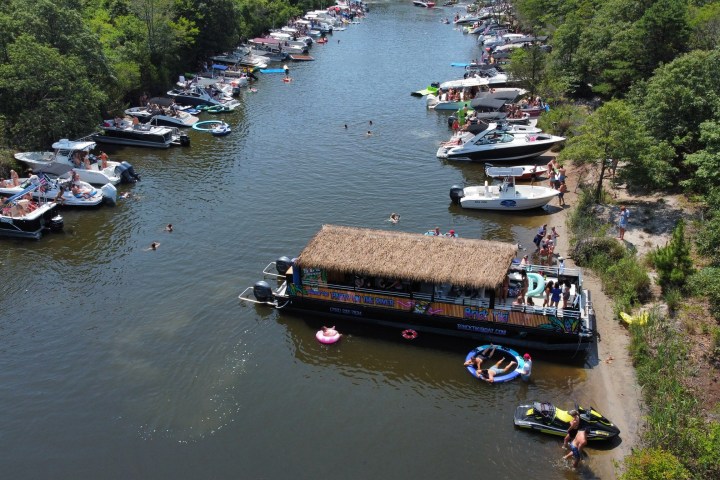 Aerial view of a crowded river with boats and people swimming.