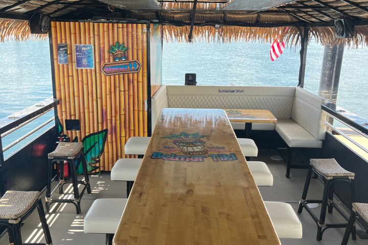 Open-air boat with bar-style seating and tiki decor on the water.