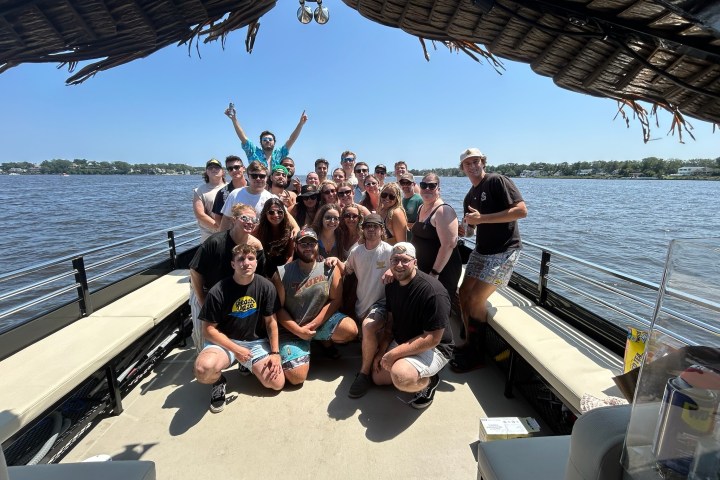 Group of people posing on a boat with a scenic lake view.