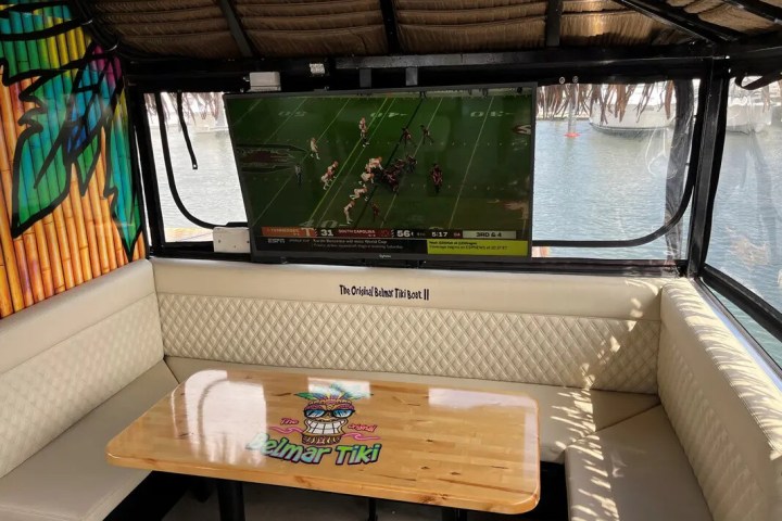 Small boat lounge with TV showing a football game, tropical theme decor.